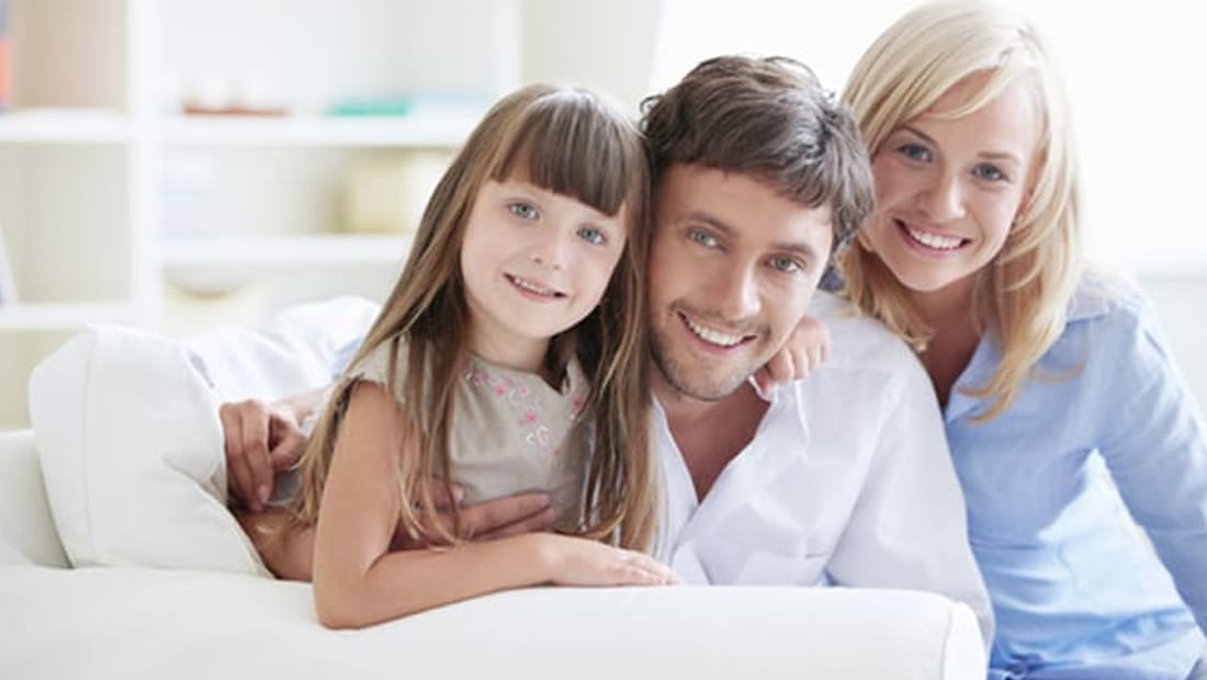 Parents and their daughter relaxing on a sofa after a move